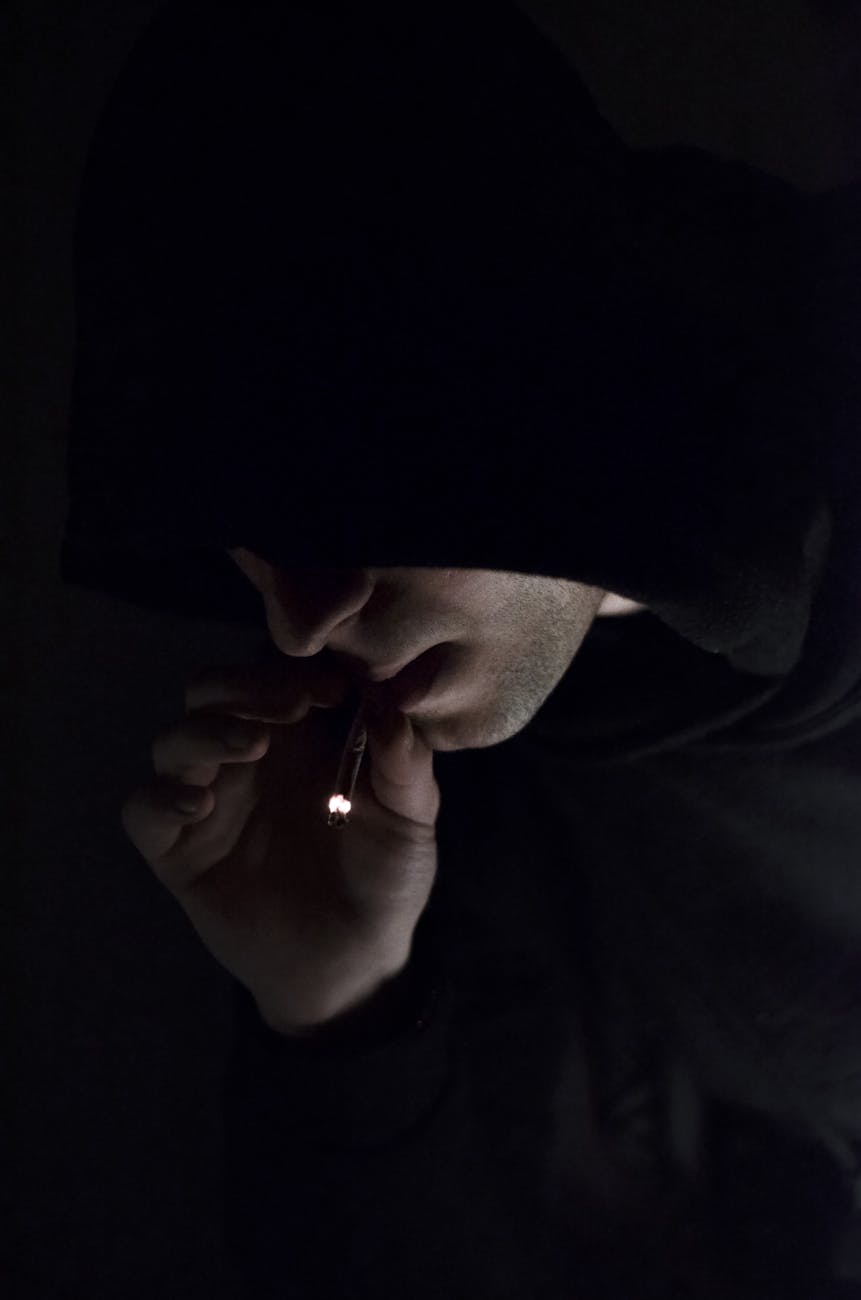 man in hoodie smoking cigarette